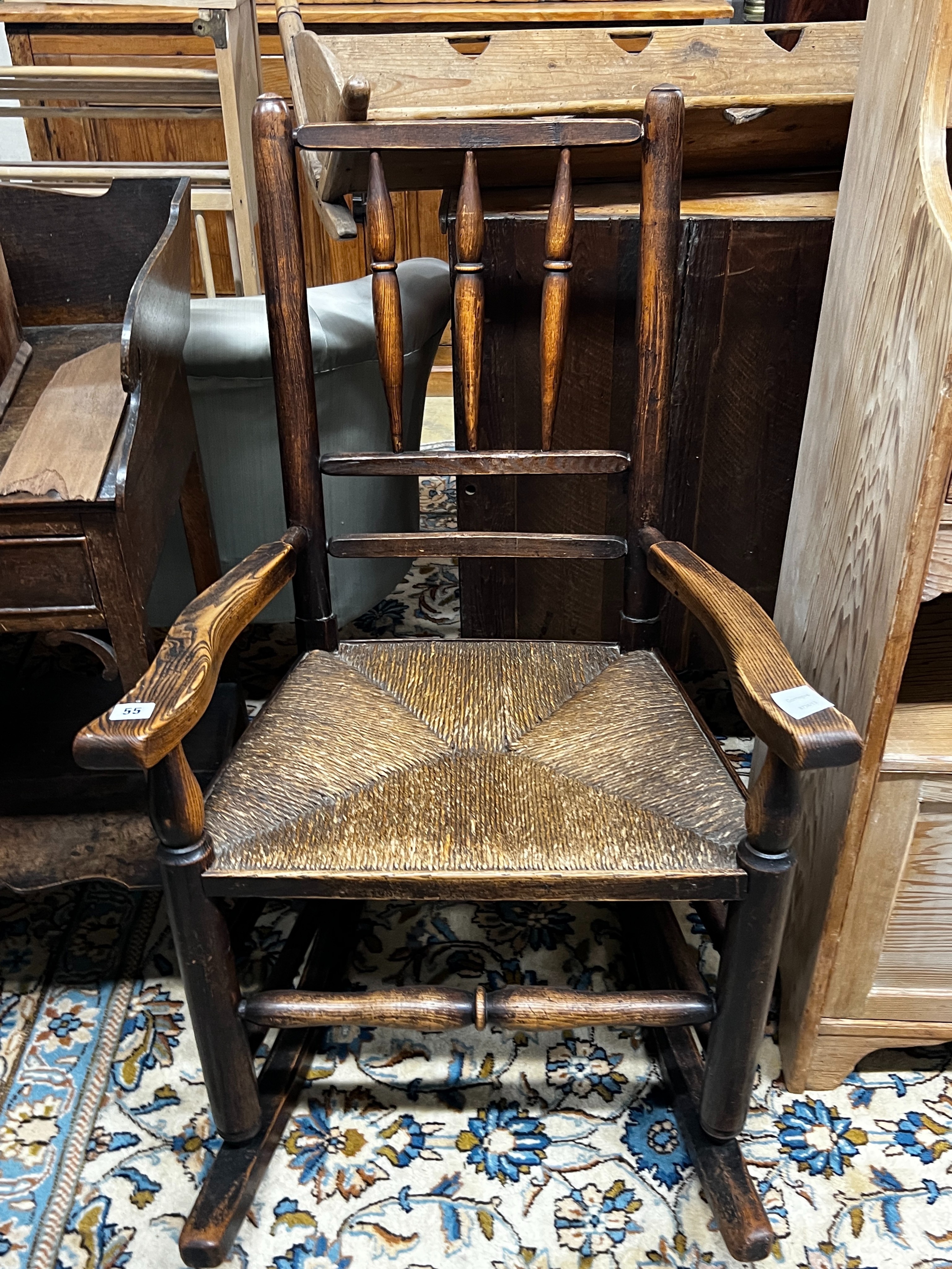 An early 19th century ash rush seat spindle back rocking chair, width 60cm, depth 46cm, height 94cm